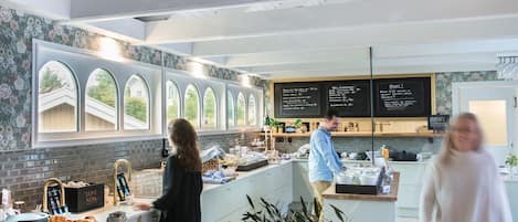 Una cocina moderna con barra desayunadora, ventanas amplias y un menú en pizarra.