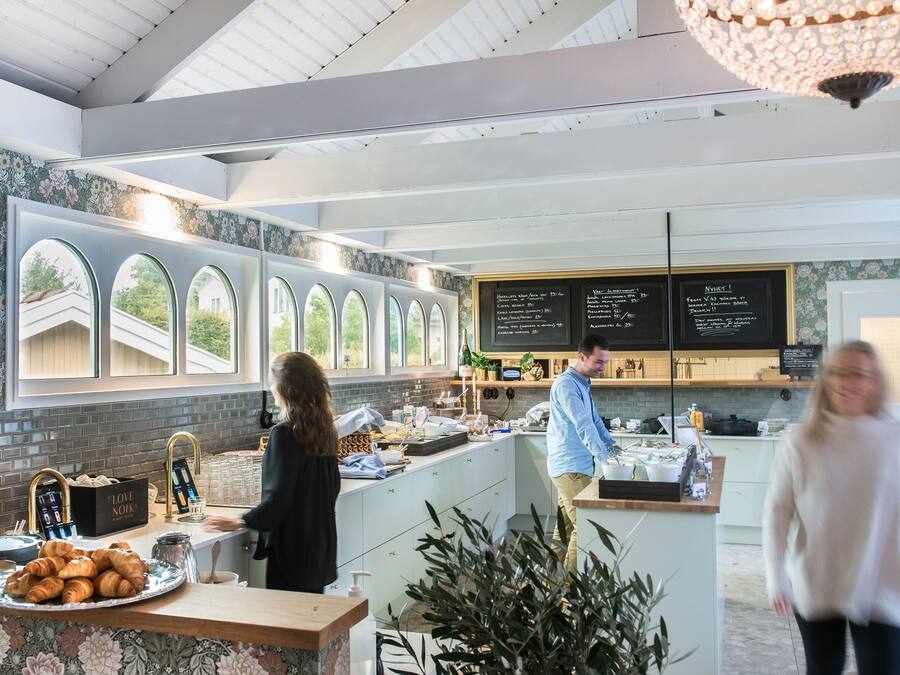 A modern kitchen with a breakfast bar, large windows, and a chalkboard menu.