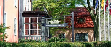 A building with a sign reading "Slottsshotellet" and flags in the background.