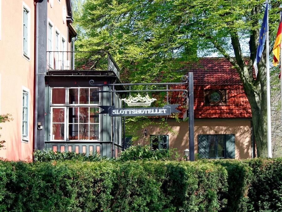 A building with a sign reading "Slottsshotellet" and flags in the background.