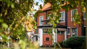 A two-story building with a red facade and white trim, featuring a balcony with a railing. - Slottshotellet Annex (Kalmar)