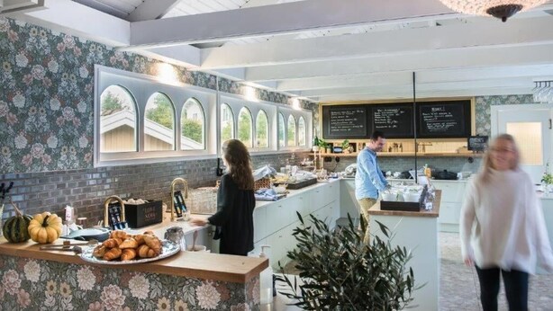 A modern kitchen area with a counter displaying pastries and a chalkboard menu. - Slottshotellet Annex (Kalmar)