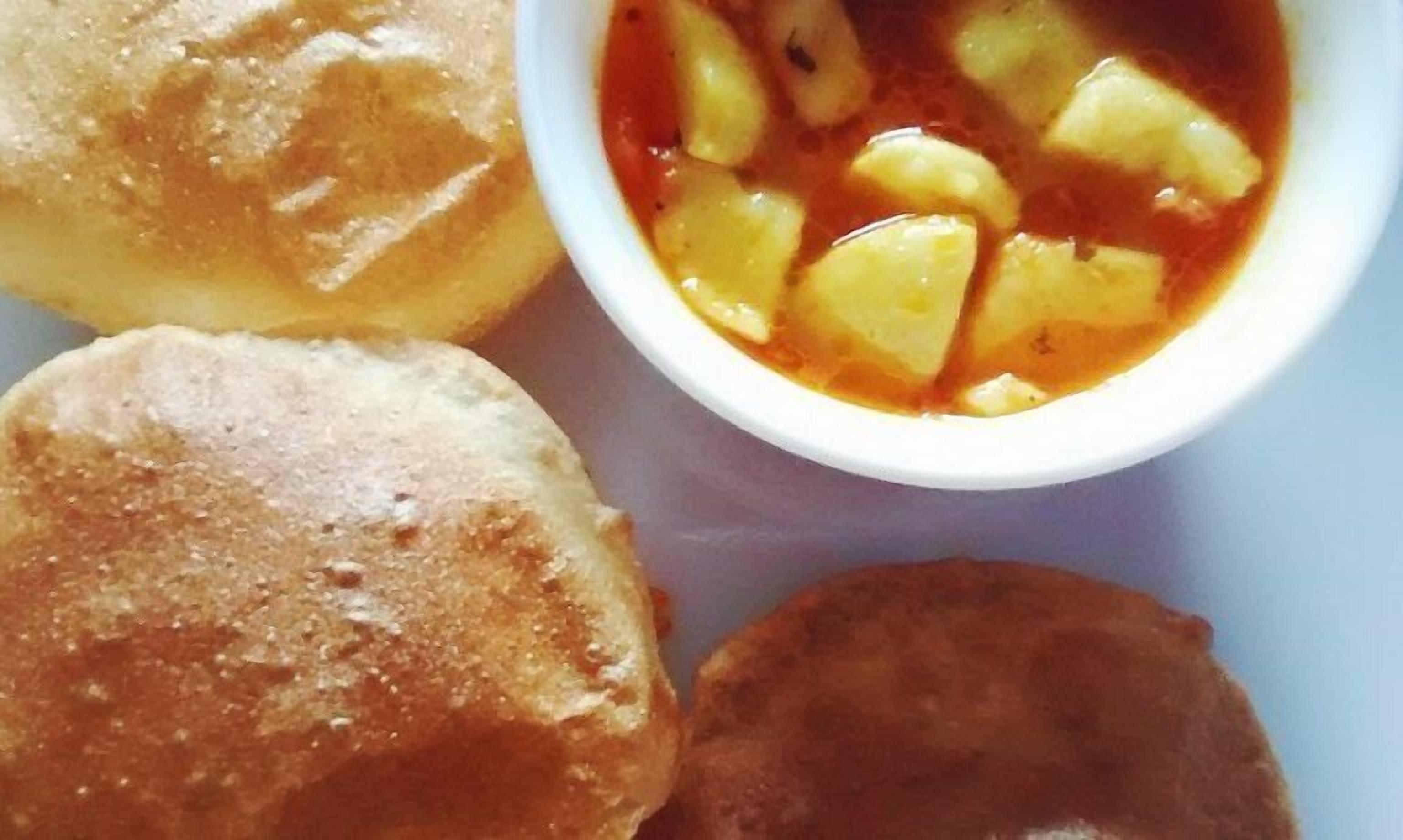 Un plato con tres piezas pequeñas y redondas de color marrón dorado y un bol con líquido rojo anaranjado con trozos.
