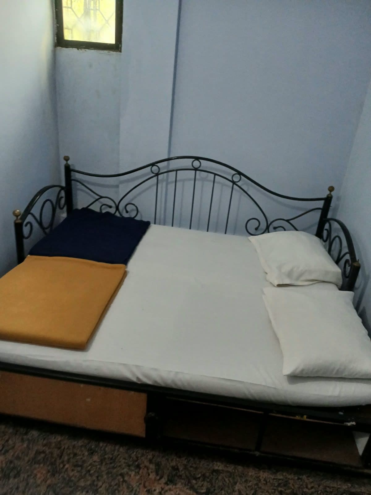 A single bed with a metal frame, a mattress, and two pillows.