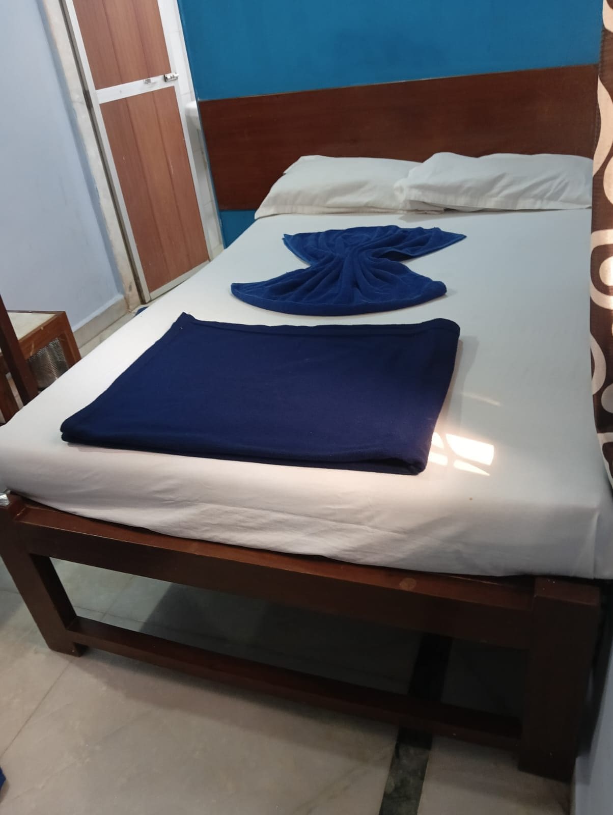 A single bed with a white mattress and a blue blanket.