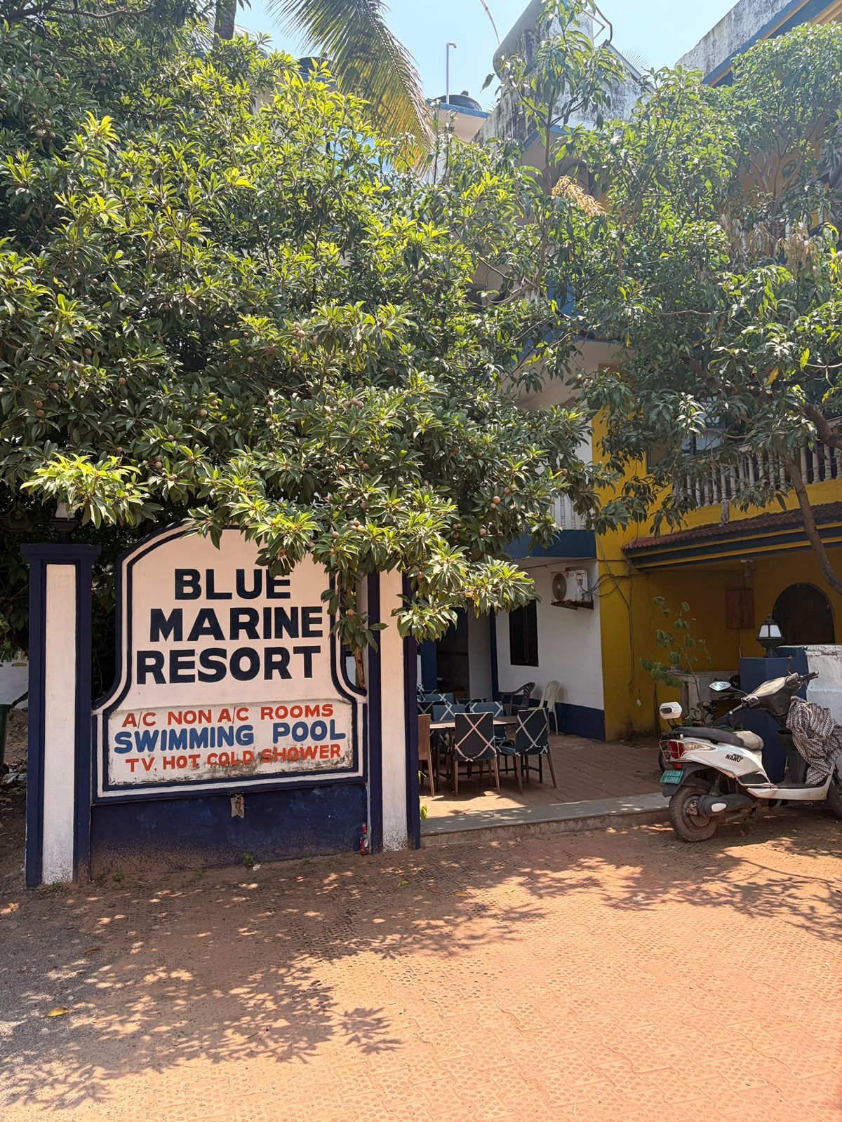 A sign for Blue Marine Resort with amenities listed including A/C, non-air-conditioned rooms, a swimming pool, TV, hot and cold showers.
