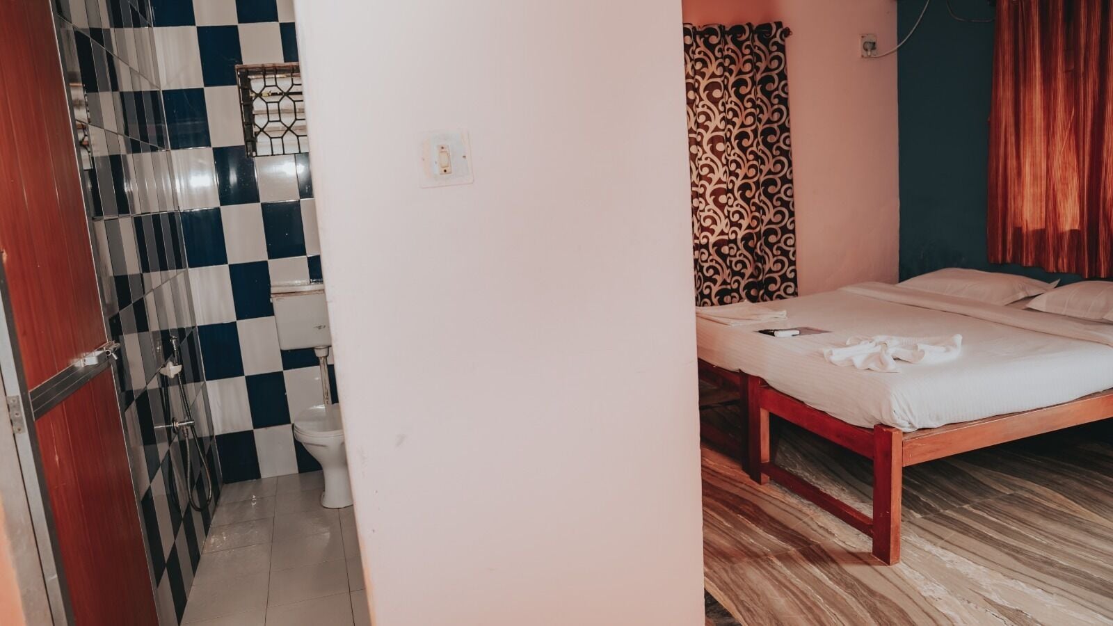 A room with a checkered floor, a bed, a toilet, and a patterned wall.