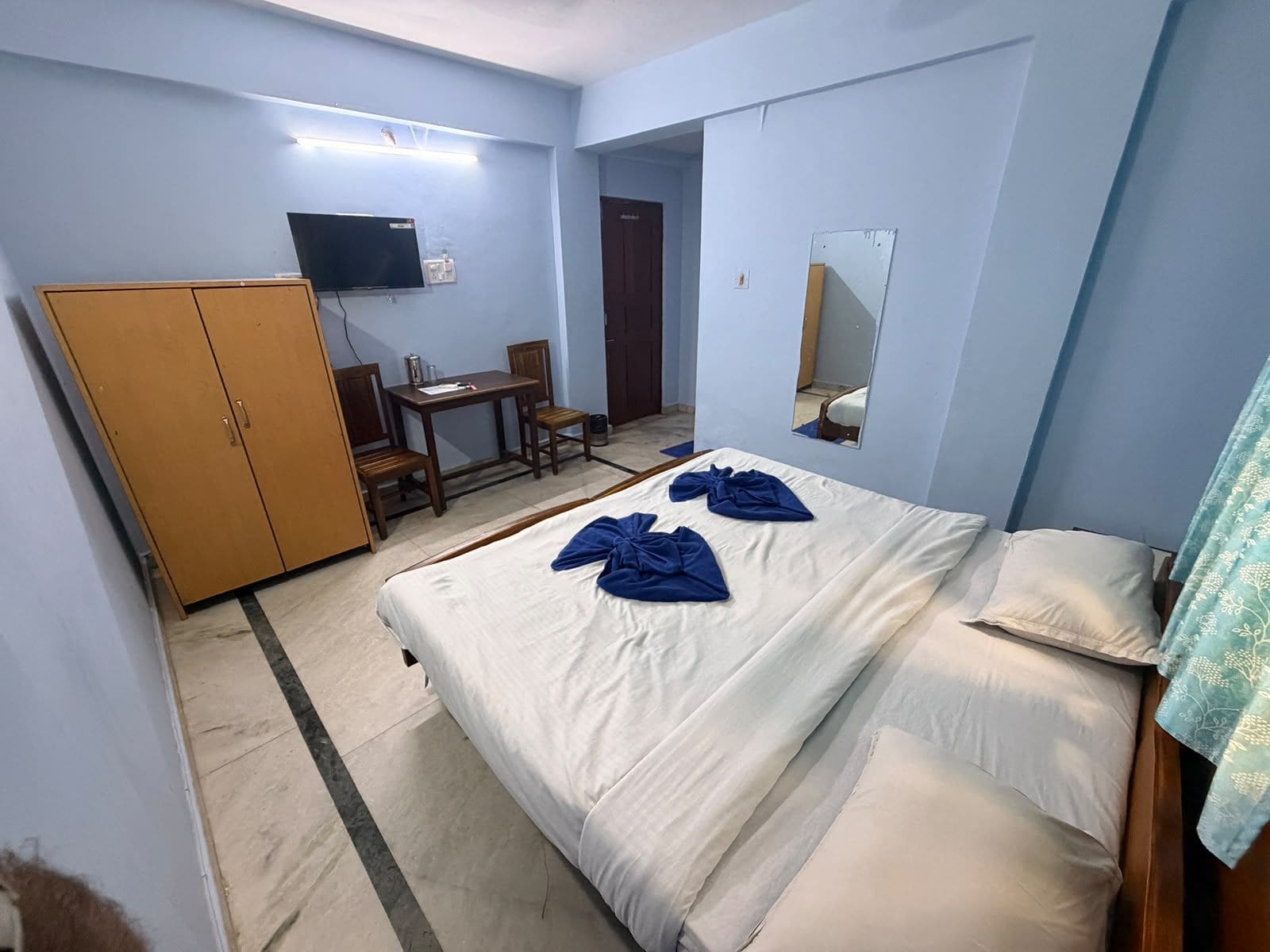 Una camera d'albergo con un letto, una scrivania, una sedia, un armadio e una televisione.