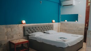 A bedroom with a large bed, a small bedside table, and a wall-mounted air conditioner. - Blue Marine Resort (Calangute)