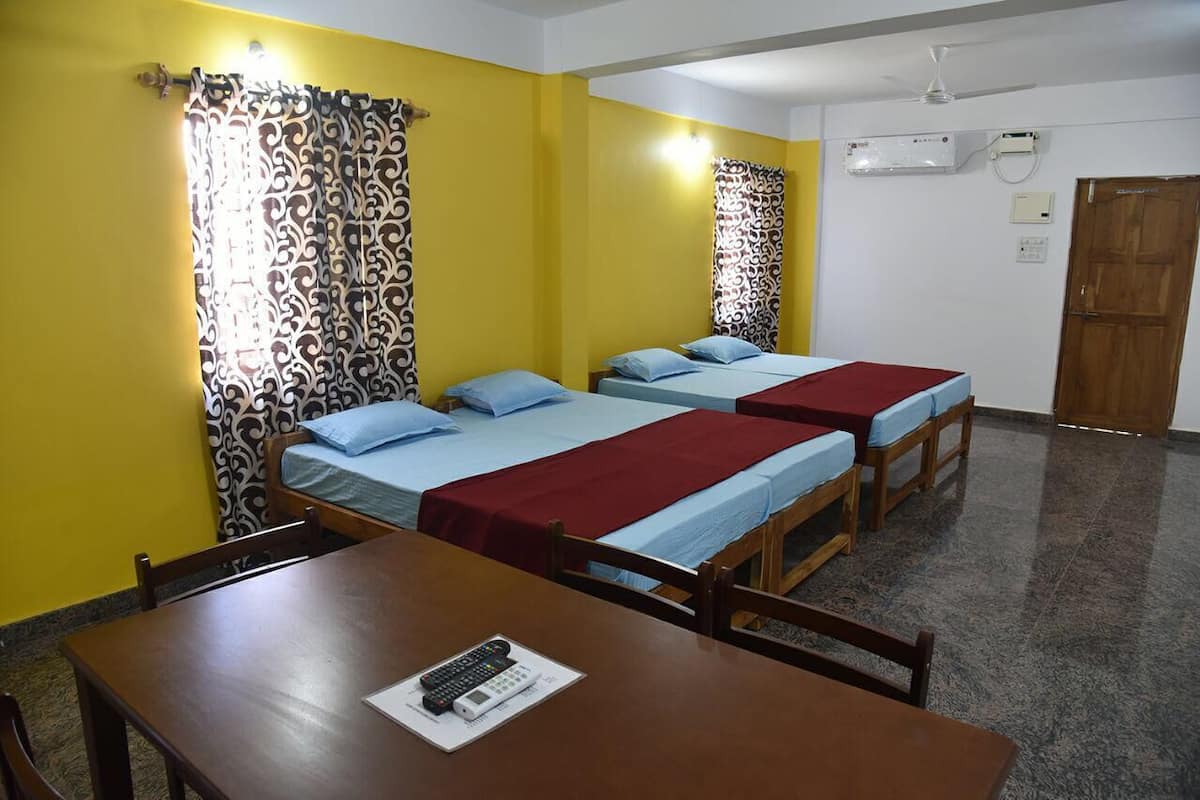 A room with two single beds, a wooden table, and a chair.
