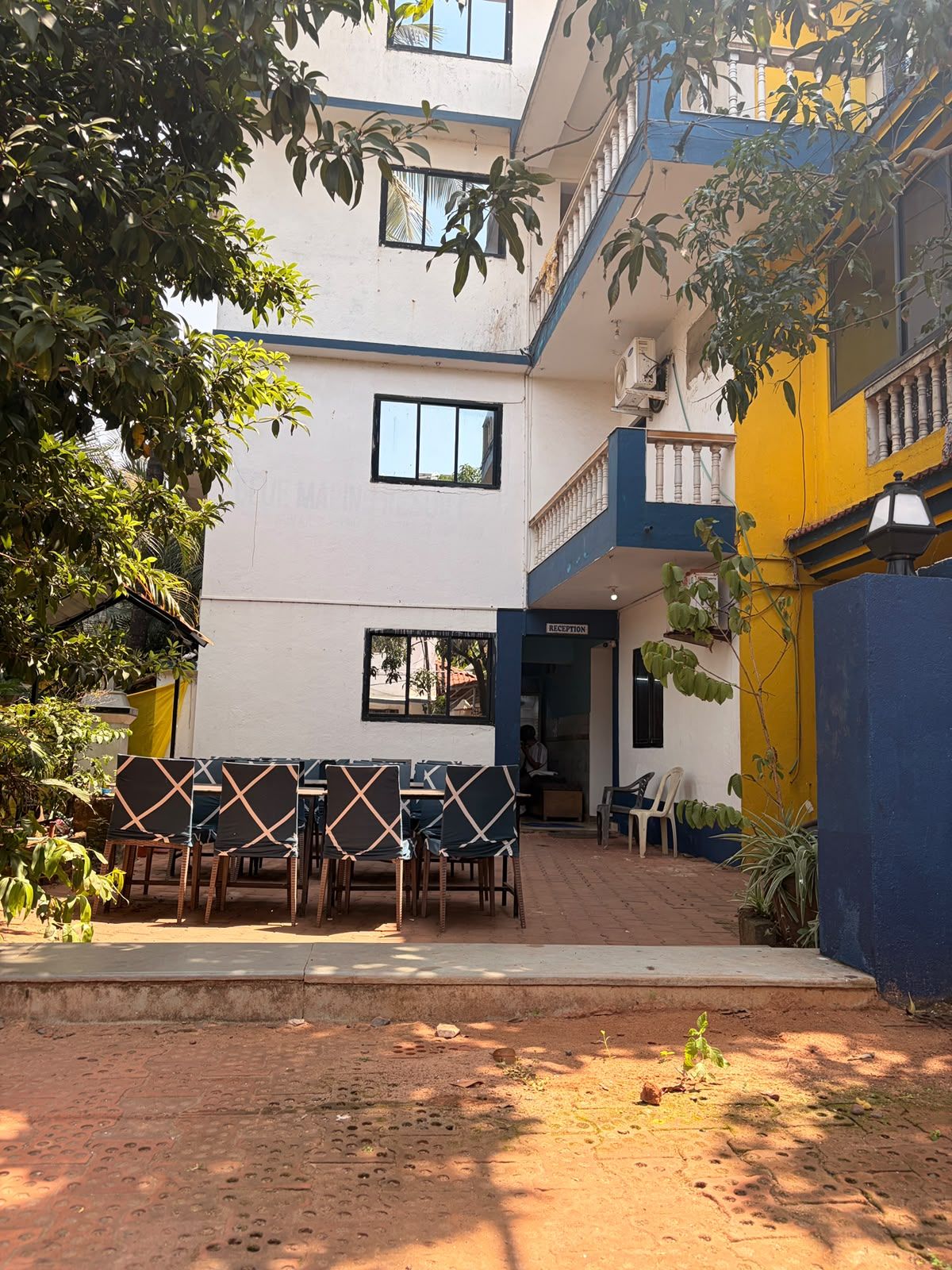 A courtyard with a reception desk, outdoor seating, and a building with multiple floors and balconies.