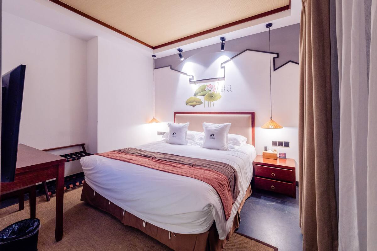 A hotel room with a bed, desk, and a TV.