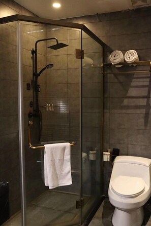 A modern bathroom with a glass-enclosed shower, a white toilet, and a towel rack with towels. - CQJ Lestay Hotel (Hangzhou)
