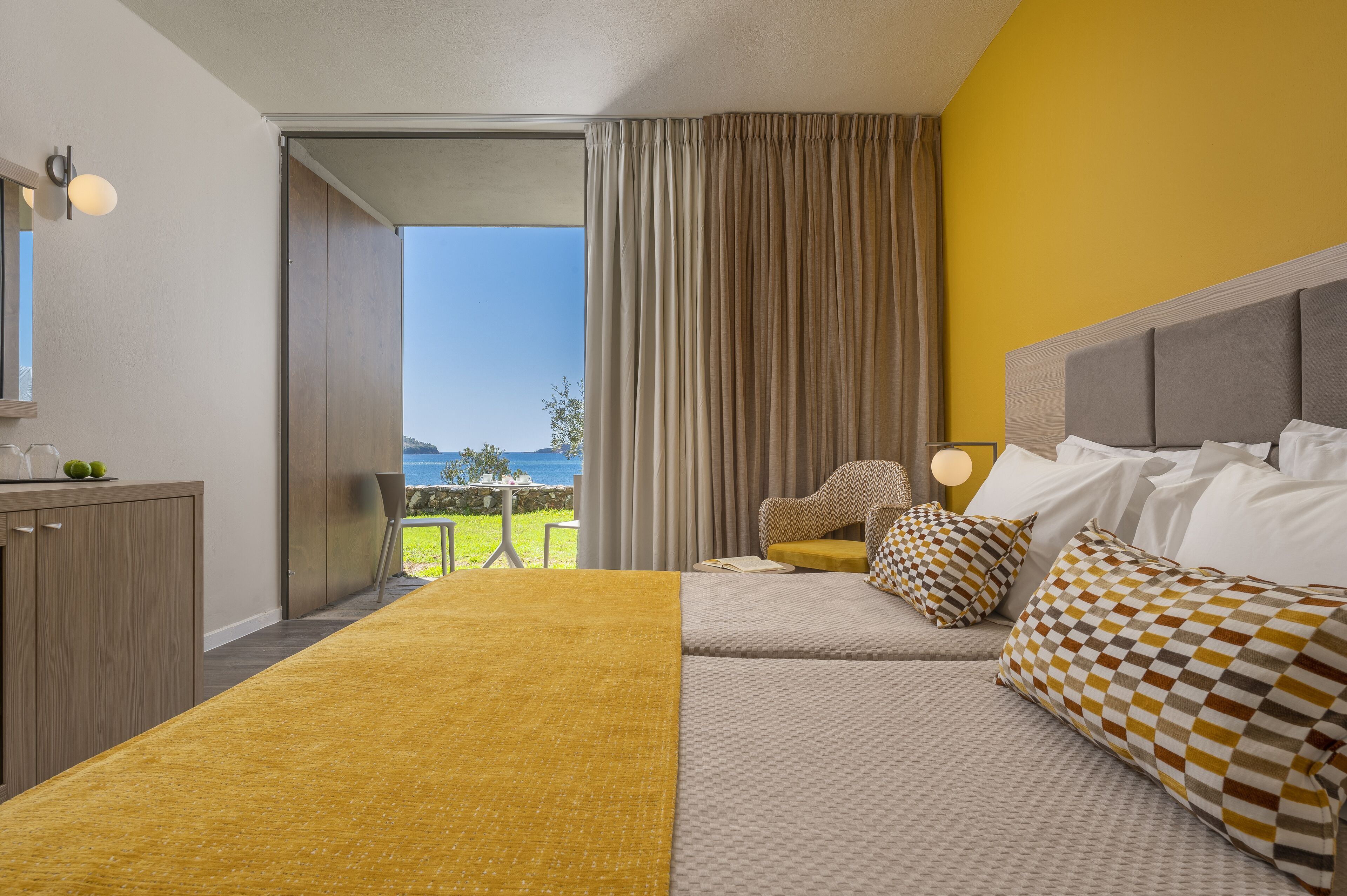 Una habitación de hotel con cama, sofá, escritorio y vista al mar.