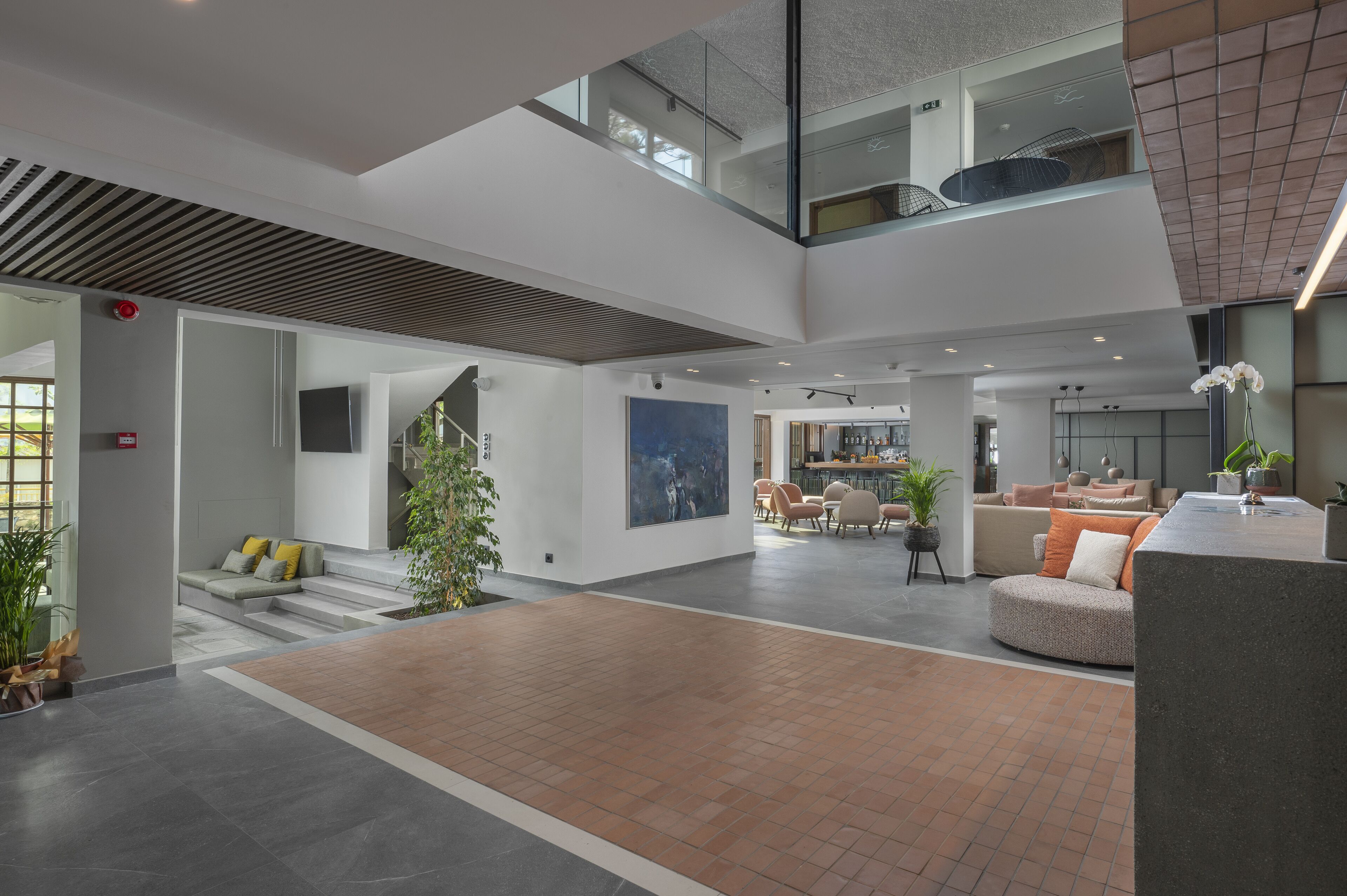 Un vestíbulo amplio con techo alto, una escalera y una zona de estar con sofás y sillones.