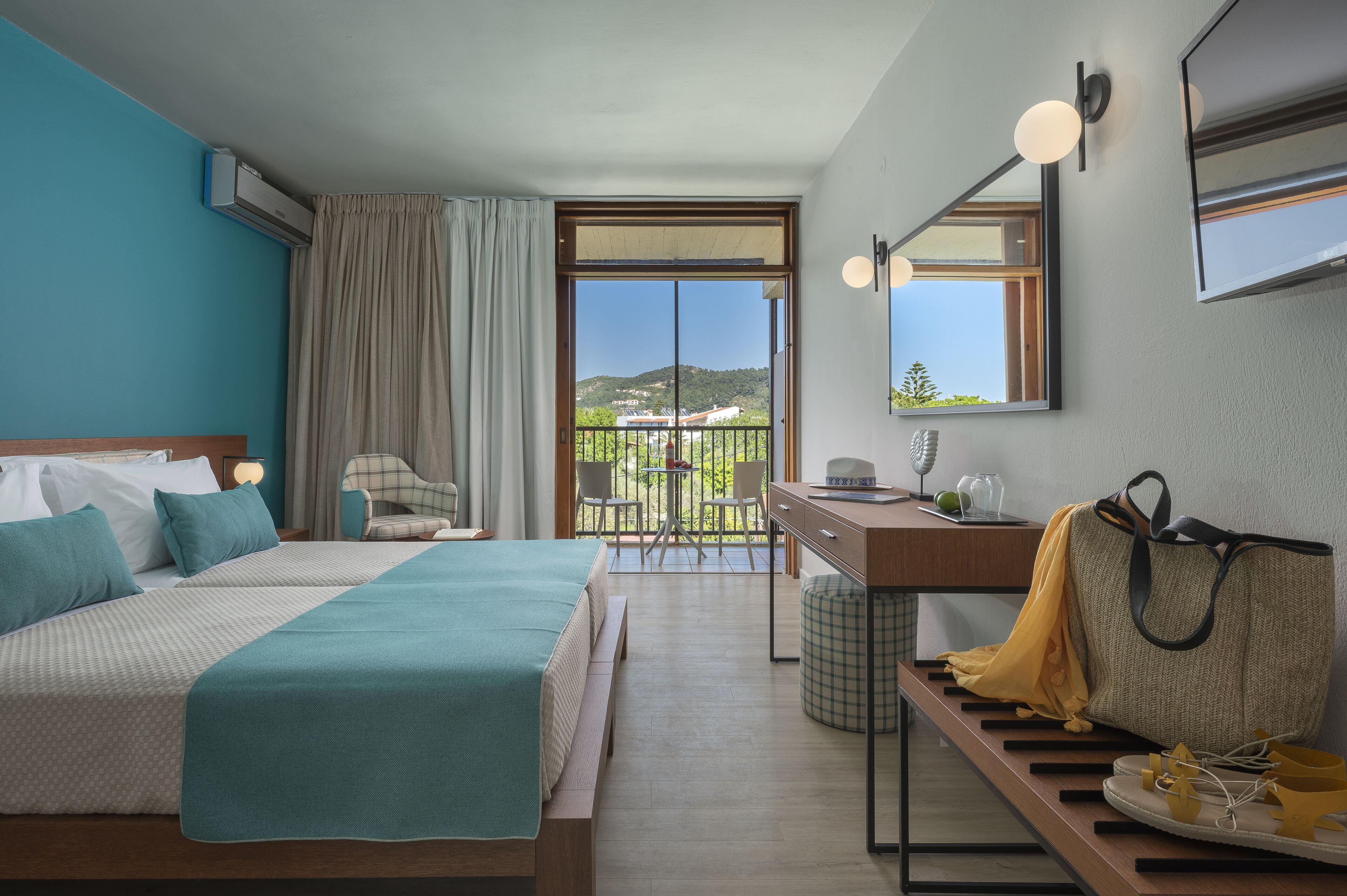 A hotel room with a bed, a desk, a chair, and a view of the outdoors.