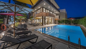 A modern hotel with a swimming pool, outdoor seating, and umbrellas. - Alkyon Hotel (Skiathos)