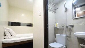 A small, compact room with a bed, a toilet, and a shower area. - Lam Shan Hotel (Kowloon)