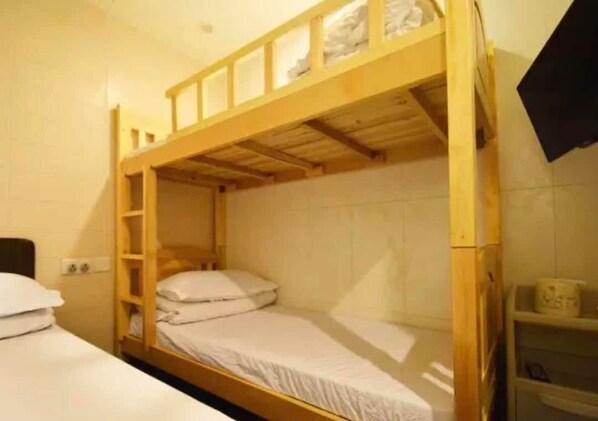 A bunk bed room with a wooden frame, white bedding, and a small shelf with a cup. - Lam Shan Hotel (Kowloon)