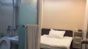 A small, compact room with a bed, a toilet, and a shower area. - Lam Shan Hotel (Kowloon)