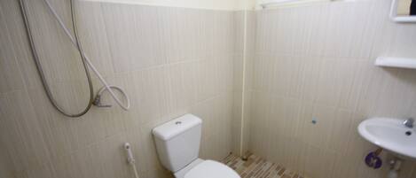 Un baño pequeño y limpio con inodoro, lavamanos y ducha.