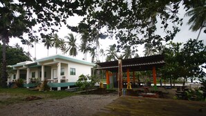 A building with a covered porch and a wooden deck. - Baan Chomlay Resort (Khanom)