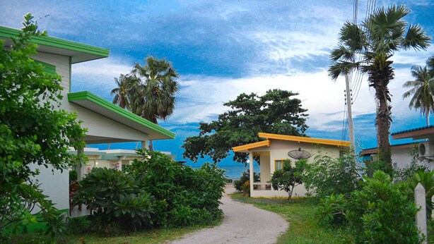 A pathway leading to a building with a satellite dish, surrounded by lush greenery and palm trees. - Baan Chomlay Resort (Khanom)