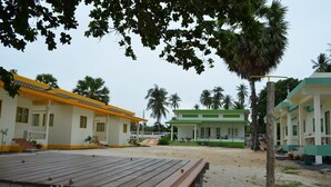 A beachside resort with multiple buildings, a sandy area, and palm trees. - Baan Chomlay Resort (Khanom)
