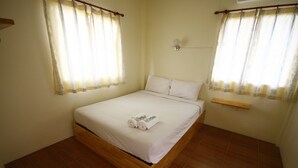 A neatly made bed with white linens and rolled towels, a wooden headboard, and a small shelf above it. - Baan Chomlay Resort (Khanom)