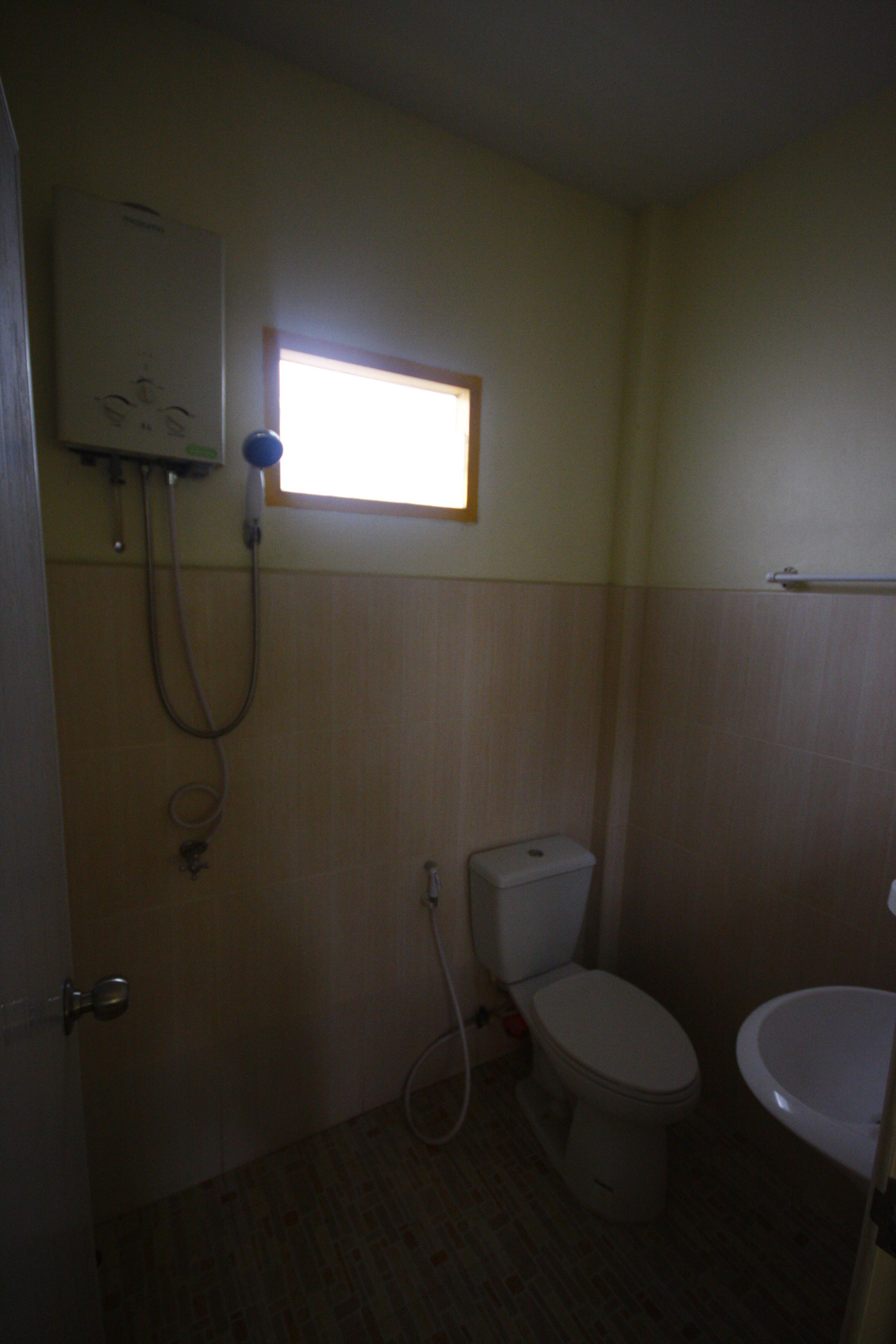 Ein kleines, schlichtes Badezimmer mit Toilette, Waschbecken und Dusche.