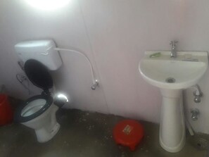 A bathroom with a toilet, a sink, and a red stool.
