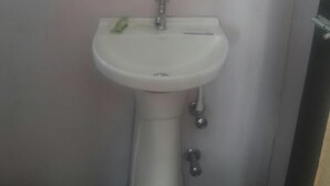 Ein weißes Waschbecken mit Spiegel darüber, einem Wasserhahn und einer Seifenspender.