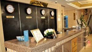 A reception desk with clocks displaying times for London, Istanbul, Almaty, and Moscow. - Renion Hills Hotel (Almaty)