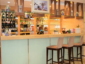 A bar area with multiple liquor bottles, glasses, and bar stools.