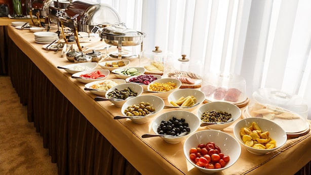 A buffet table with various food items and serving utensils. - Renion Hills Hotel (Almaty)