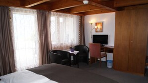 Une chambre d’hôtel avec un lit, un bureau avec un ordinateur, une chaise et un téléviseur.