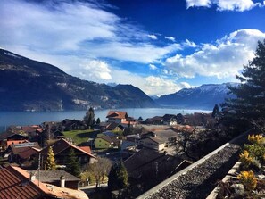 Un pueblo a orillas del lago con casas tradicionales, cielo despejado y montañas al fondo.
