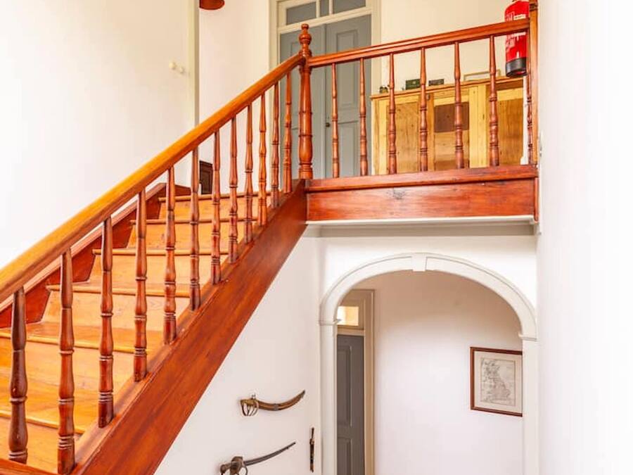 A wooden staircase with a blue railing leading to a balcony.