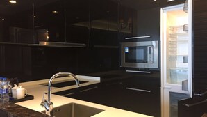 A modern kitchen with a stainless steel sink, a built-in oven, and a microwave. - Checkinn Business Apartment-Poly World (Guangzhou)