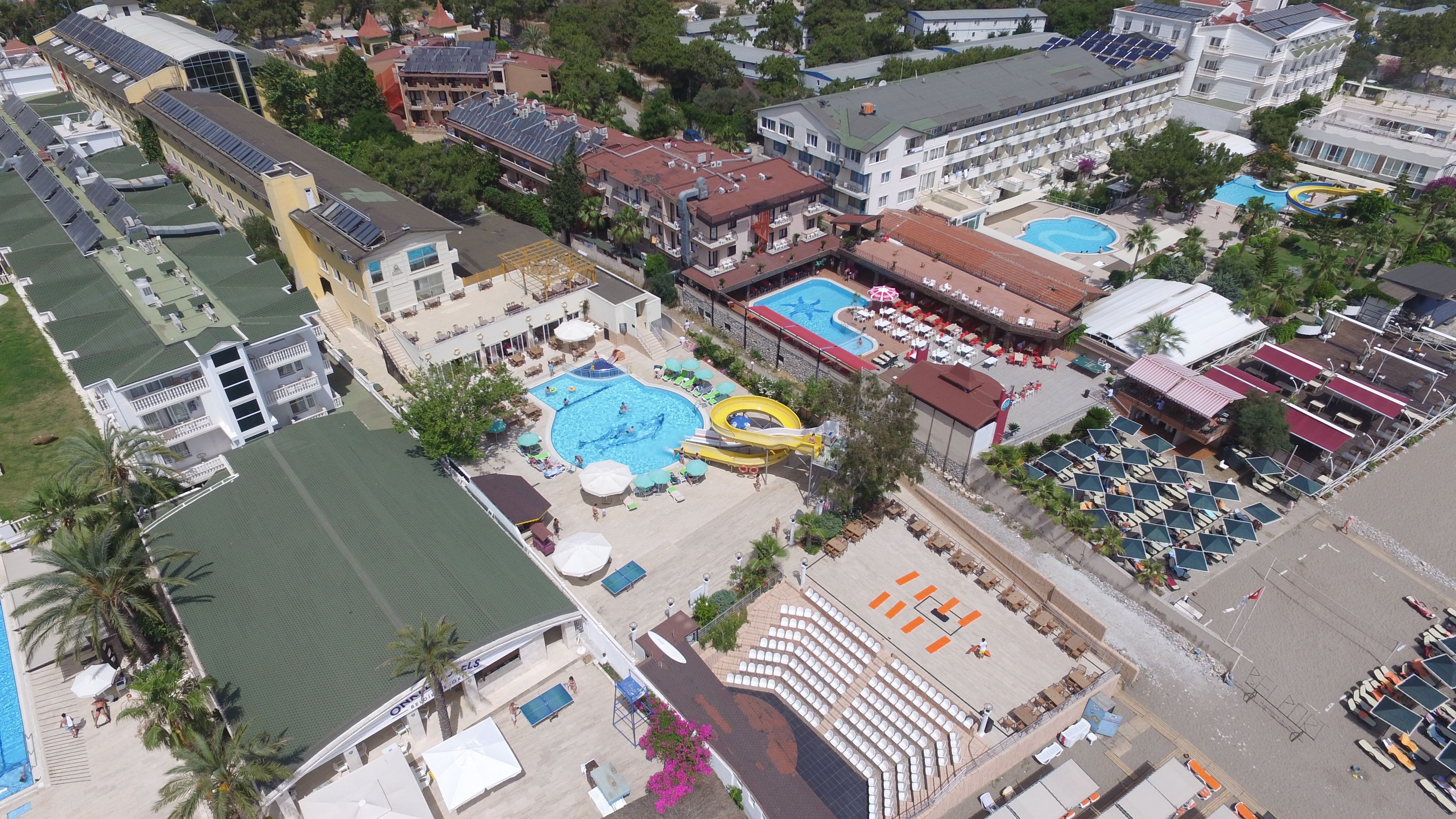 An aerial view of a resort with multiple swimming pools, a water slide, and a large outdoor seating area.