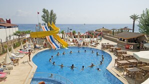 A pool area with a water slide, lounge chairs, and a view of the sea. - Club Hotel Sunbel - All Inclusive (Kemer)