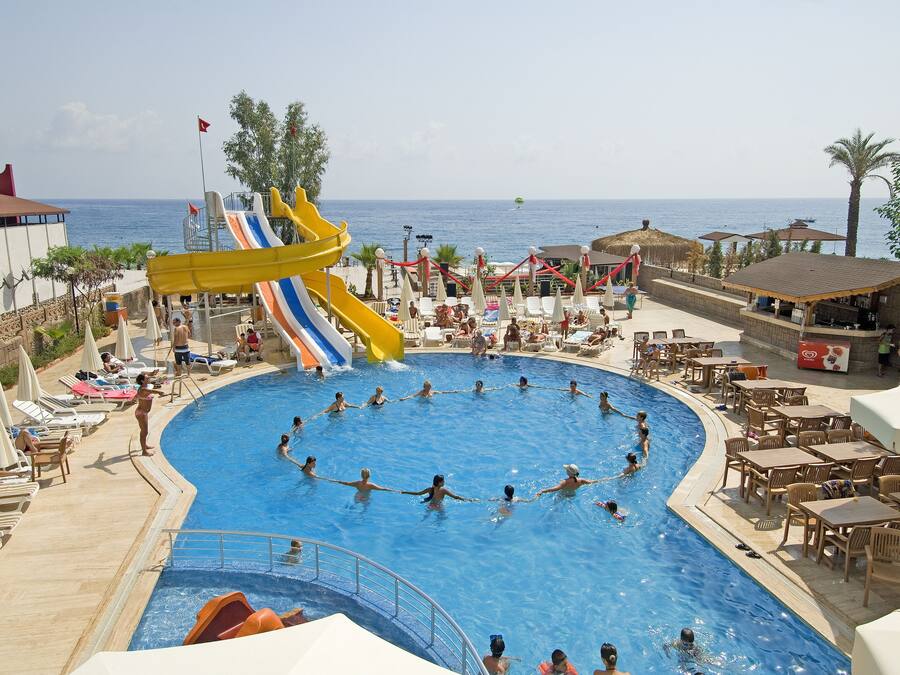 A pool area with a water slide, lounge chairs, and a view of the sea.