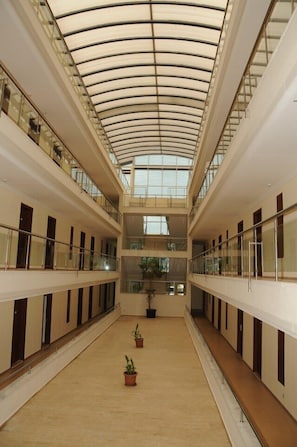 A multi-level atrium with a curved glass ceiling, potted plants, and a central walkway. - Club Hotel Sunbel - All Inclusive (Kemer)