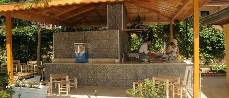 An outdoor bar area with a stone counter, wooden chairs, and a covered seating area.