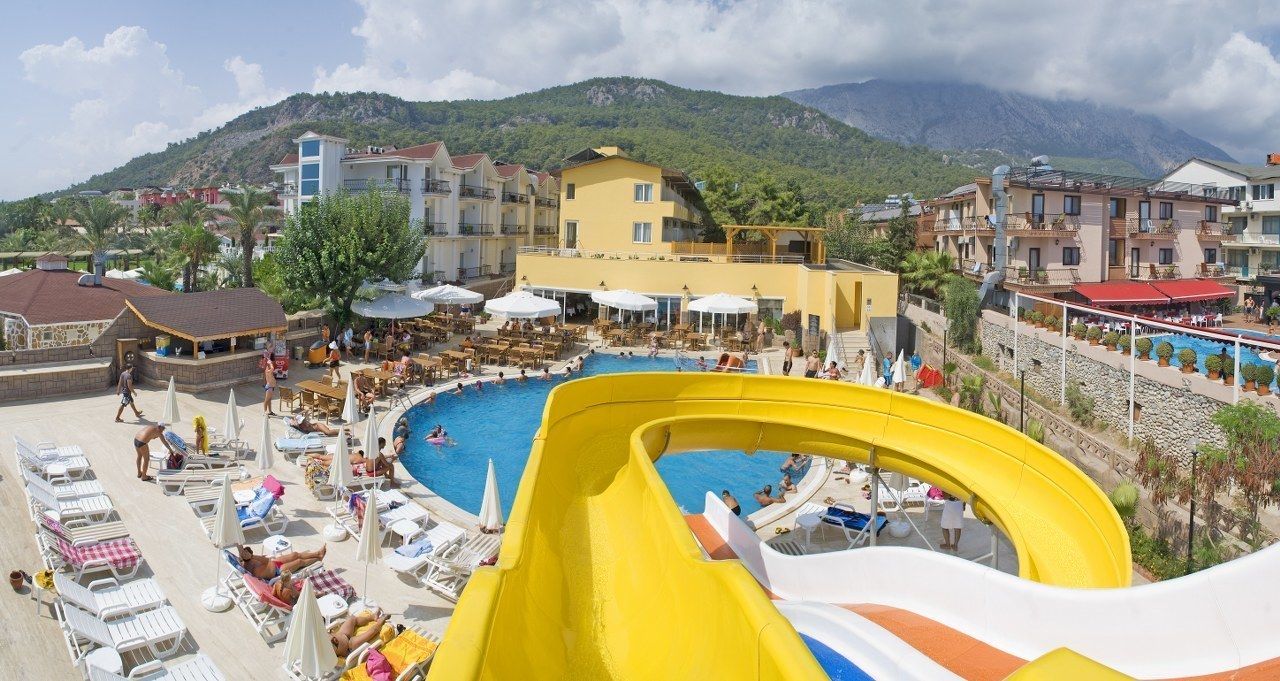 Un complejo turístico con una piscina grande, un tobogán acuático y vistas a las montañas.