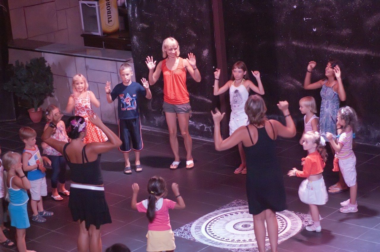 Un grupo de niños y adultos en un escenario con un fondo estrellado, posiblemente en un teatro o espacio para eventos.