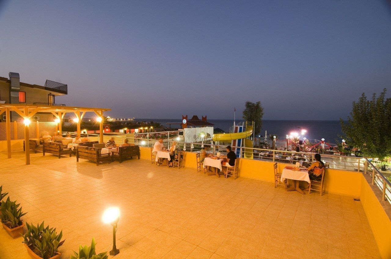 An outdoor dining area with tables and chairs, overlooking the sea.
