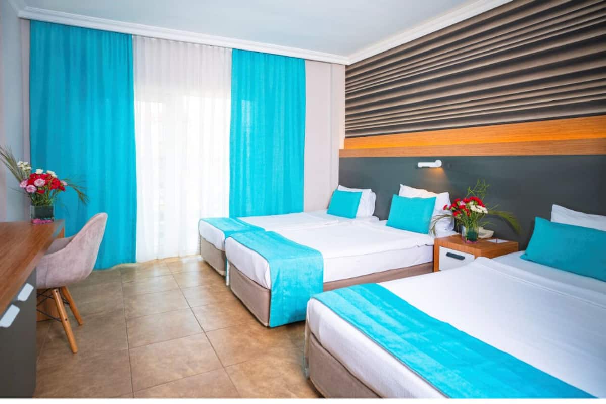 A hotel room with two beds, a desk, and a chair.