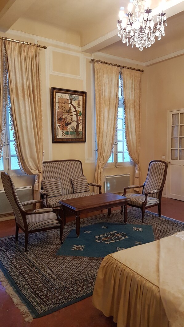 Una habitación con candelabro, sofás a rayas, alfombra estampada y una obra de arte enmarcada en la pared.
