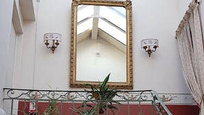 A staircase with a red railing, a large mirror, and potted plants. - Hôtel Cardinal (Aix-en-Provence)